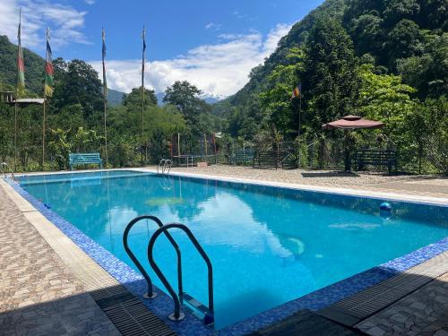 una piscina blu con una montagna sullo sfondo di The Mandarine Retreat a Mangan