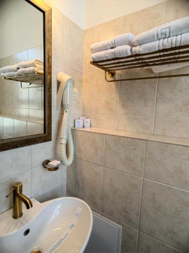 ein Badezimmer mit Waschbecken, Spiegel und Handtüchern in der Unterkunft Hotel Carol in Constanţa