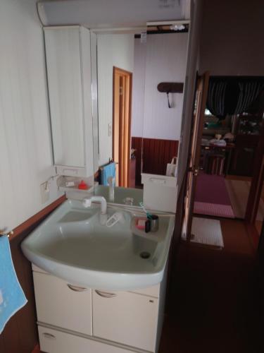 uma casa de banho com um lavatório e um espelho em 玉川温泉の湯治に最適な宿　鳳凰館 em Senboku