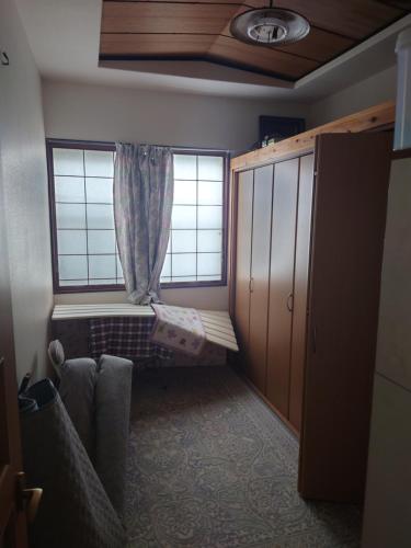 Habitación pequeña con 1 cama y 2 ventanas en 玉川温泉の湯治に最適な宿　鳳凰館, en Senboku