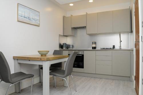 uma cozinha com armários brancos e uma mesa e cadeiras em Luxury 5 Star apartments, Parking, Garden, near Metro Stations 10-15mins to London em Londres