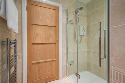 a bathroom with a shower and a wooden door at The Granary at Pannels Ash Farm in Sudbury