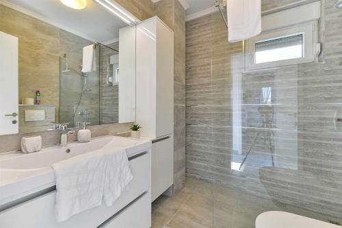 ein weißes Bad mit einem Waschbecken und einer Dusche in der Unterkunft Laudato XXL DELUXE in Turanj