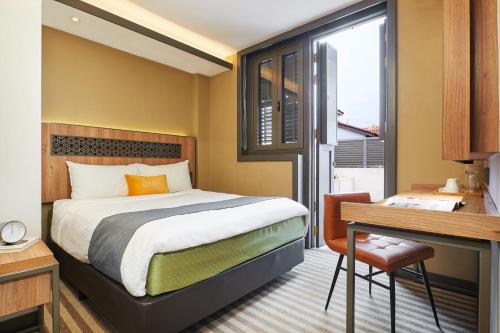um quarto de hotel com uma cama, uma secretária e uma janela em Dash Living Rochor em Singapura