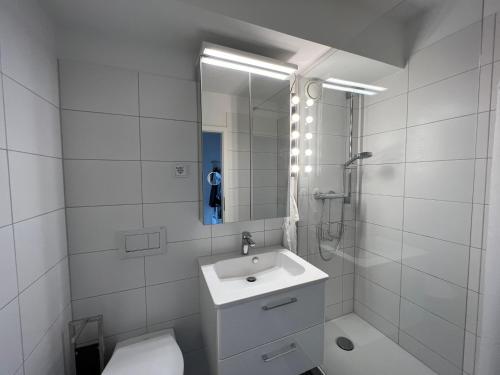 a white bathroom with a sink and a shower at Apartment Domblick in Cologne