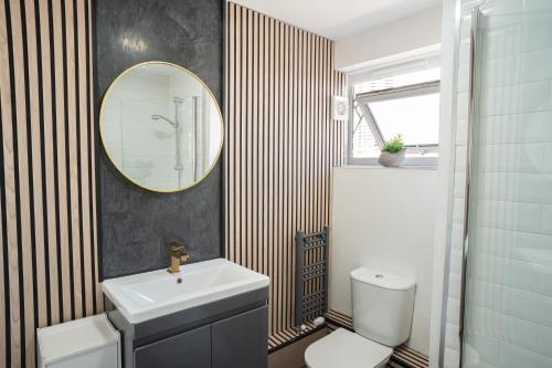 W łazience znajduje się umywalka, toaleta i lustro. w obiekcie Olympic apartment - Stratford w Londynie