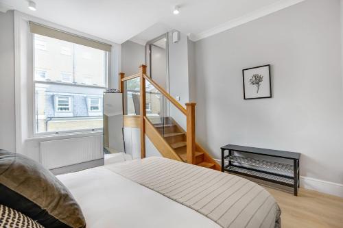 a bedroom with a bed and a stair case at Phaedrus Living: South Kensington Luxury Flat in London