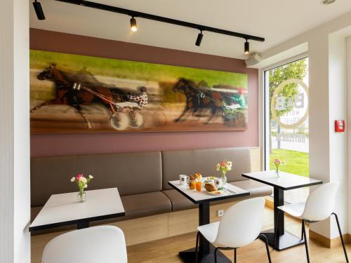 ein Restaurant mit zwei Tischen und einem Gemälde an der Wand in der Unterkunft B&B Hotel Mönchengladbach in Mönchengladbach