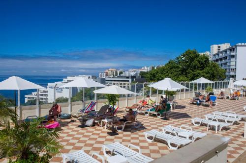 a group of people sitting on a patio with chairs and umbrellas at Florasol Residence Hotel - Dorisol hotels in Funchal