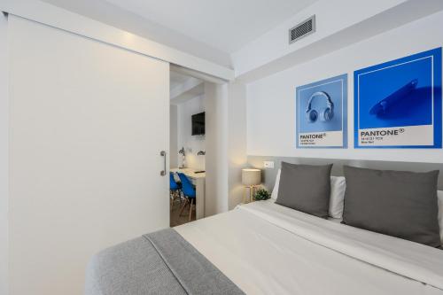 a white bedroom with a bed and a desk at AmazINN Places Blasco de Garay 102 in Madrid