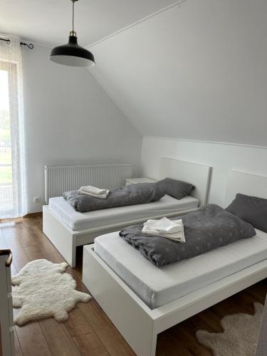 Habitación con 2 camas, paredes blancas y suelo de madera. en Bokorlak 3 en Odorheiu Secuiesc