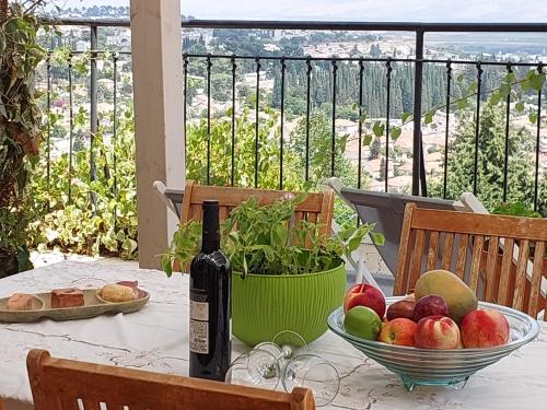 een tafel met een fles wijn en een fruitschaal bij Neve Nof in Rosh Pinna