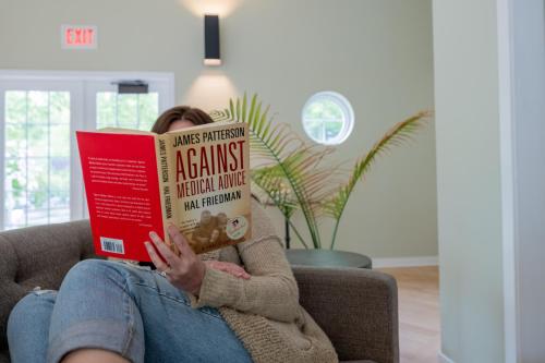 a woman sitting on a couch reading a book at Villa Signor in Norwich