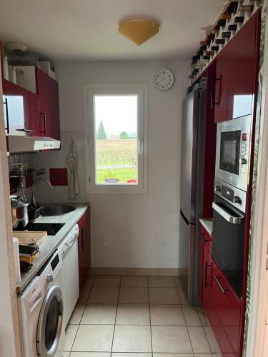 une cuisine avec des placards rouges et une fenêtre dans l'établissement Résidence Claire Rive Appt 45, à Prayssac