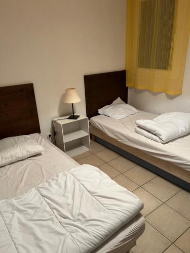 une chambre avec deux lits et une lampe sur une table de chevet dans l'établissement Résidence Claire Rive, à Prayssac