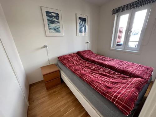 a bed with a red comforter in a room at Nydelig ferieleilighet på bryggekanten in Korshamn