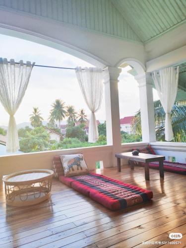 a living room with a couch and a large window at 天堂鸟花园客栈 in Luang Prabang
