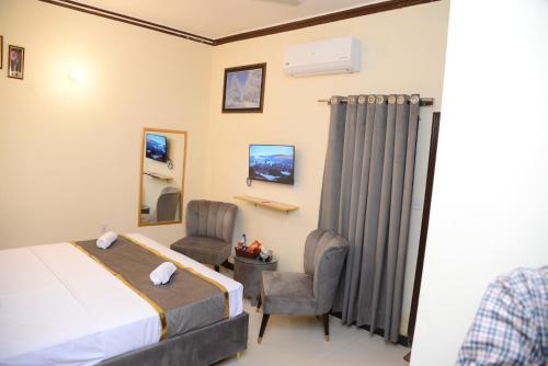 a hotel room with a bed and two chairs at Go Room Hotel Lahore in Lahore