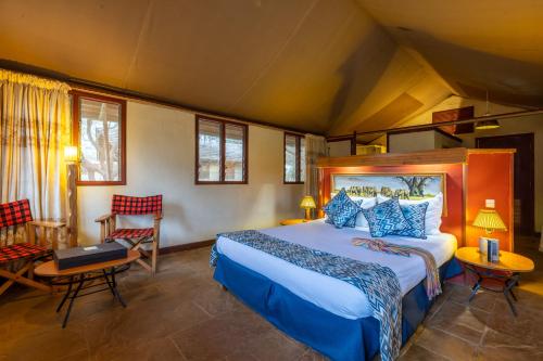 ein Schlafzimmer mit einem Bett und Stühlen in einem Zimmer in der Unterkunft Sentrim Amboseli Lodge in Amboseli-Nationalpark