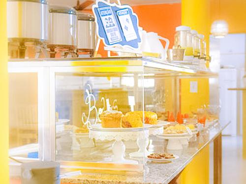 a display case in a kitchen with pastries on display at VELINN Pousada Casa de Pedra Ilhabela in Ilhabela