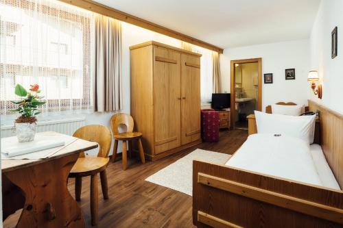 a bedroom with a bed and a table and chairs at Hotel Komperdell in Serfaus