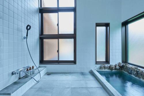 baño con piscina y bañera con ventanas en VOYAN RESORT 伊豆MADOKA, en Futo