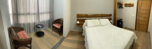 a bedroom with a bed and a room with a chair at Pousada & Hospedagem Estação in Domingos Martins