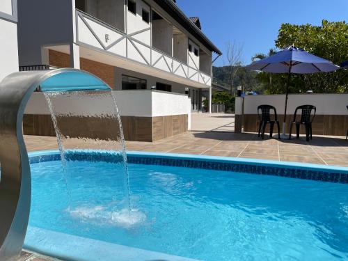 a pool with a water fountain in front of a building at Pousada & Hospedagem Estação in Domingos Martins
