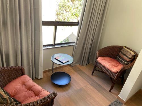 a living room with two chairs and a table and a window at Pousada & Hospedagem Estação in Domingos Martins