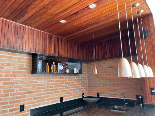 a kitchen with a brick wall and wooden ceiling at Hospedagem Estação in Domingos Martins