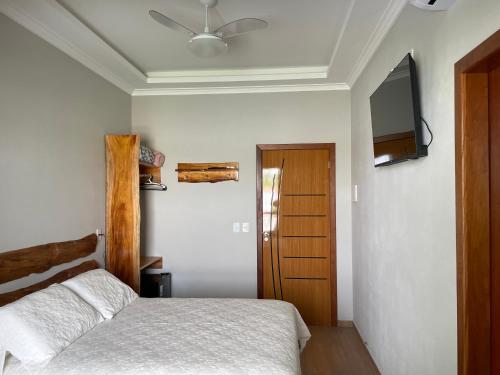 a bedroom with a bed and a flat screen tv at Pousada & Hospedagem Estação in Domingos Martins
