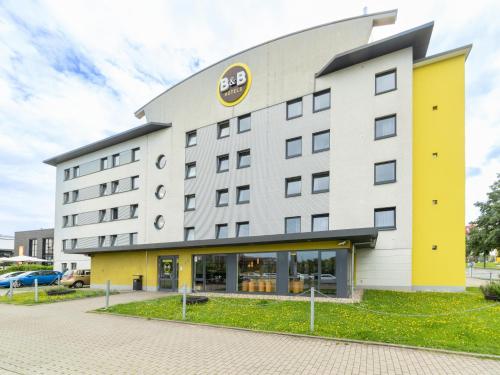 a hotel with a yellow and white building at B&B Hotel Oberhausen am Centro in Oberhausen