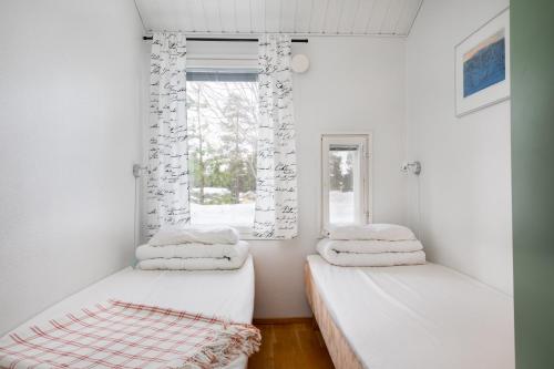 two beds in a room with a window at Levilehto Apartments in Levi