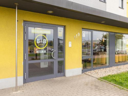 um edifício amarelo com uma porta com um sinal em B&B Hotel Oberhausen am Centro em Oberhausen