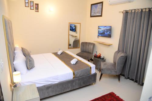 a bedroom with a bed and two chairs and a mirror at Go Room Hotel Lahore in Lahore