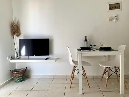 a dining room with a table and chairs and a tv at Casa D'oro A1 in Larisa