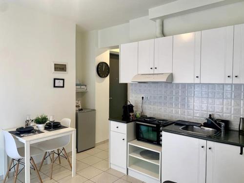 a kitchen with white cabinets and a table and a sink at Casa D'oro A1 in Larisa