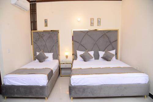 a bedroom with two beds with white sheets and pillows at Go Room Hotel Lahore in Lahore