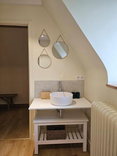 a bathroom with a sink and mirrors on the wall at Les chambres de la Vaulx-Renard in La Gleize