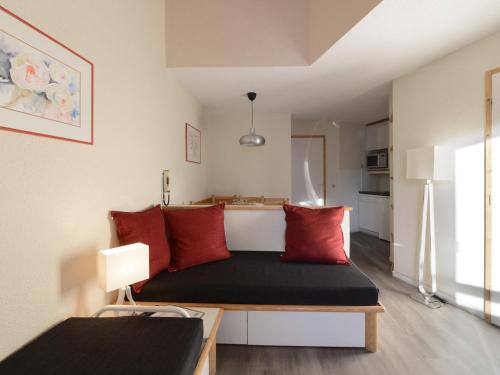 Cette petite chambre comprend un lit avec des oreillers rouges. dans l'établissement Appartement confortable au pied des pistes avec balcon | 5 pers - FR-1-181-2031, à La Plagne Tarentaise