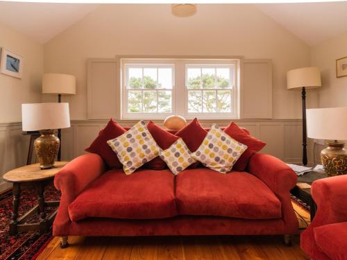 a living room with a red couch with pillows at Rosecott in St Ives