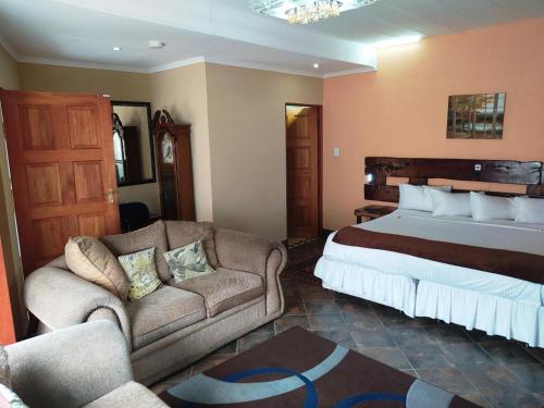 a hotel room with a bed and a couch at Acre of Africa Guesthouse in Boksburg