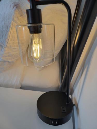 a black lamp on a wall next to a bed at Stone House Kenora in Kenora