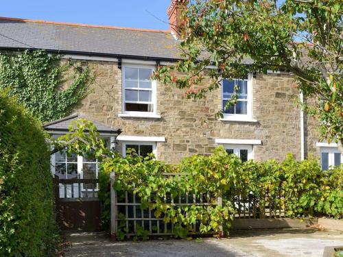 a brick house with a fence in front of it at Mellow Cottage just a short walk to the beach in Perranporth