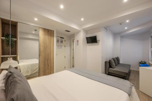um quarto com uma cama branca e uma cadeira em AmazINN Places Blasco de Garay 113 em Madri