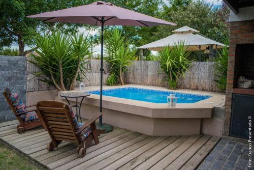uma piscina com um guarda-sol, uma cadeira e uma mesa em La Esquina - hermosa casa en Termas del Daymán em Termas del Daymán