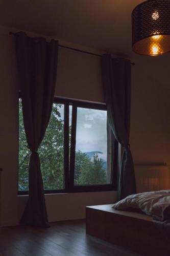a bedroom with a bed and a large window at The Hygge House in Plopi
