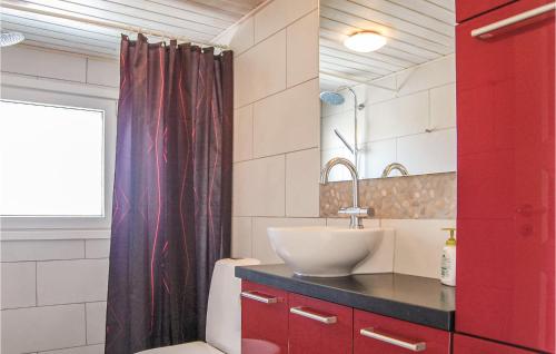a bathroom with a sink and a red shower curtain at 4 Bedroom Gorgeous Home In Hvide Sande in Havrvig