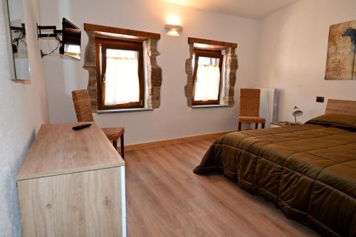 a bedroom with a bed and a desk and windows at Il Sogno in Acquapendente