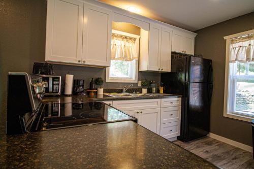 a kitchen with white cabinets and a black refrigerator at Mountain Haven Dragon's Nest Cabin in Robbinsville